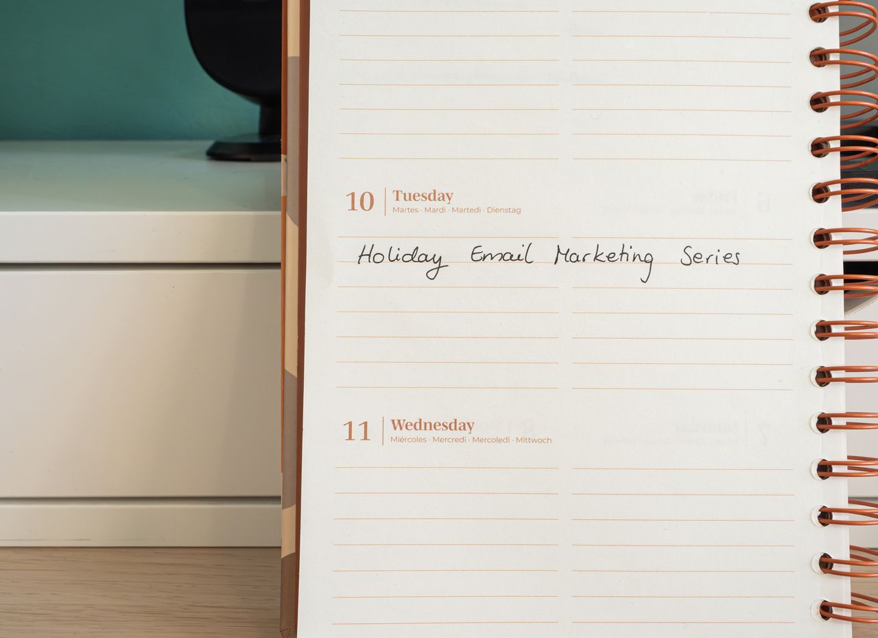 Planner open on a desk with handwritten Holiday Email Marketing Series note.